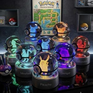 May include: A collection of spherical glass lamps featuring internal 3D laser-etched Pokemon figures, each resting on a circular base labeled with names like Pikachu, Mewtwo, Gengar, and Bulbasaur. A Pokemon Kanto Region Trainer Map poster hangs behind the lamps.