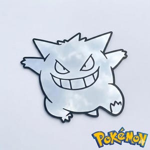 May include: A mirror in the shape of a Gengar, a Pok&eacute;mon character, with a black outline. The mirror reflects the sky and clouds. The Pok&eacute;mon logo is in the bottom right corner.