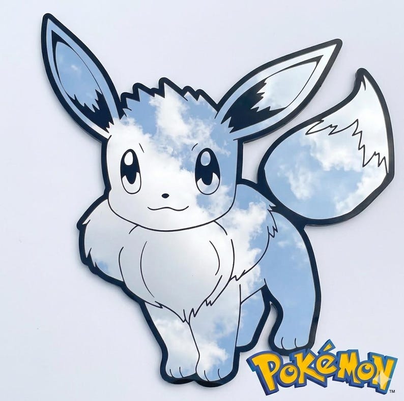 May include: A mirror shaped like the Pok&eacute;mon character Eevee, with a sky and cloud design. The character is outlined in black, with a white and blue cloud pattern filling the shape. The Pok&eacute;mon logo is in the bottom right corner.