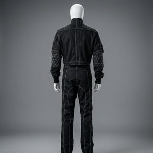 K&ouml;nnte beinhalten: Schwarzer Rennanzug mit wei&szlig;en Steppn&auml;hten. Der Anzug hat einen hohen Kragen, lange &Auml;rmel und eine Hose. Geometrische Steppmuster befinden sich auf den Schultern und &Auml;rmeln. Der Anzug wird auf einer Schaufensterpuppe vor grauem Hintergrund pr&auml;sentiert.