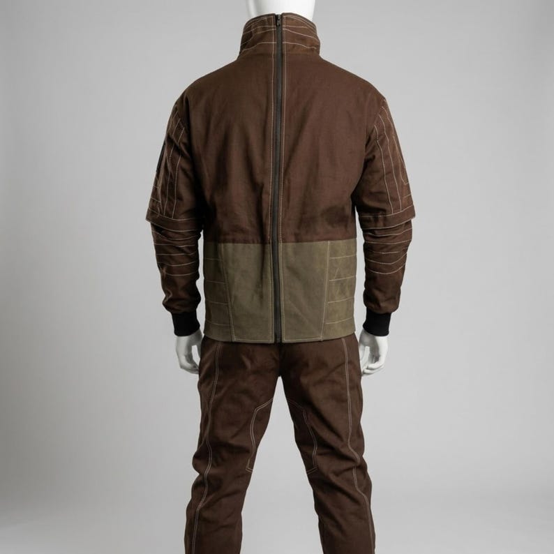 May include: A brown two-piece outfit with a jacket and pants. The jacket has a high collar, a full-length zipper, and olive green panels at the waist. The pants are brown with matching stitching. The outfit is displayed on a mannequin.