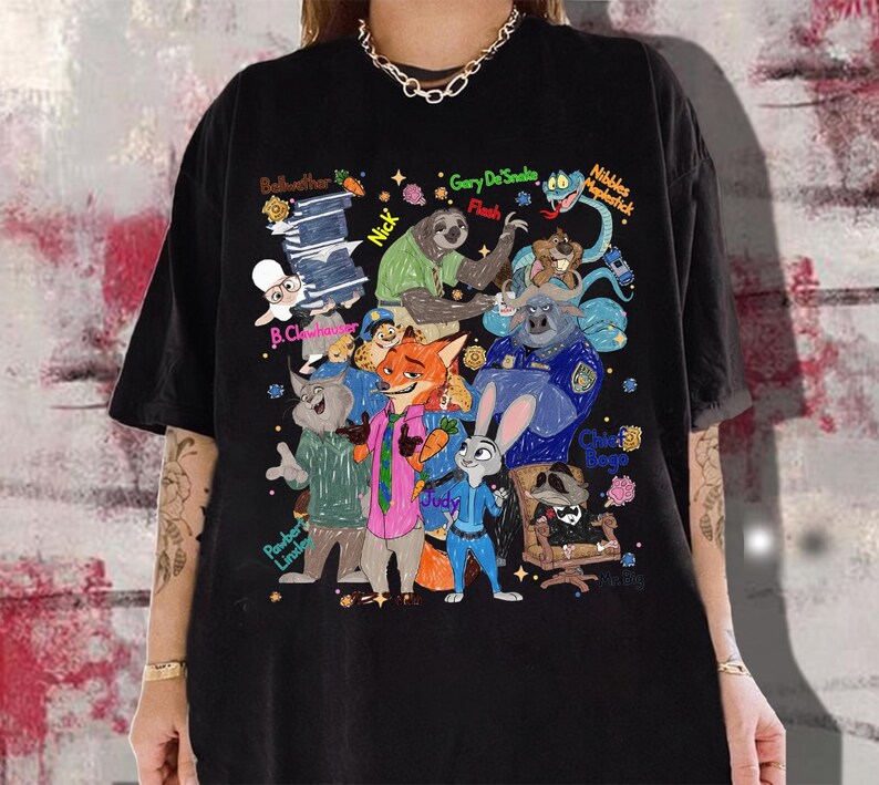 Op de afbeelding: Zwart T-shirt met een kleurrijke illustratie van personages uit de animatiefilm Zootopia. Het ontwerp bevat verschillende dierenpersonages met hun namen, zoals Judy, Nick en Flash. Het shirt is een casual kledingstuk.