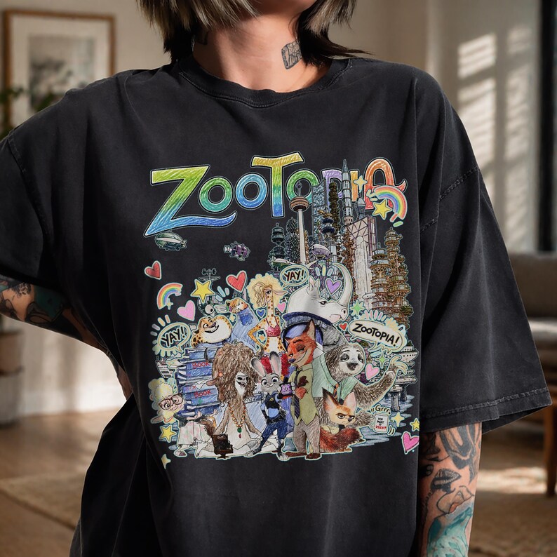 May include: Black t-shirt featuring a colorful graphic from the animated movie Zootopia. The design includes the word "Zootopia" in large, stylized letters, along with various characters and elements from the film. The shirt has a vintage, worn look.