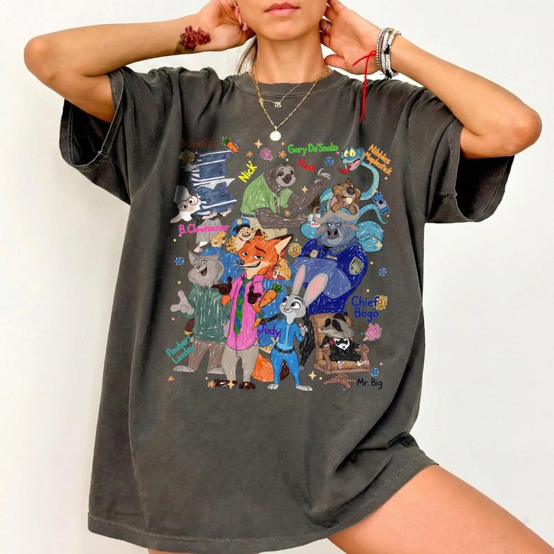 Op de afbeelding: Donkergrijs T-shirt met een kleurrijke afbeelding van personages uit de animatiefilm Zootopia. Het ontwerp bevat Judy Hopps, Nick Wilde, Chief Bogo en andere personages. Het shirt heeft een vintage, versleten uitstraling.