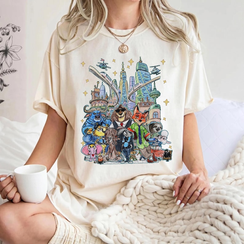 K&ouml;nnte beinhalten: Cremefarbenes T-Shirt mit einer farbenfrohen Illustration verschiedener Tierfiguren in einer Stadtkulisse. Das Design zeigt eine Stadtlandschaft mit Geb&auml;uden, einer Einschienenbahn und Hubschraubern. Die Charaktere sind vielf&auml;ltig, mit einem L&ouml;wen im Anzug und einem Fuchs im gr&uuml;nen Hemd.