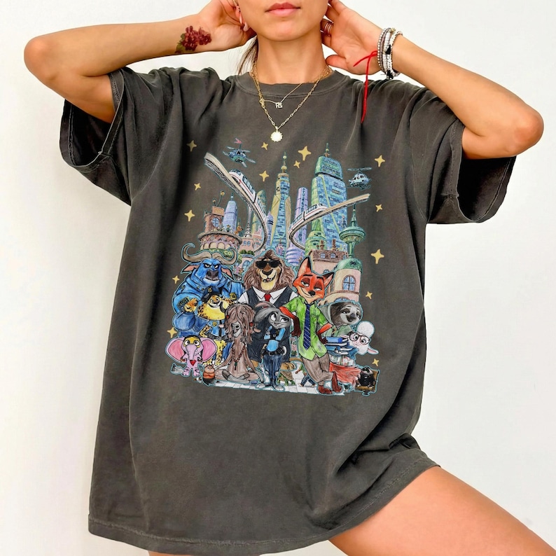 K&ouml;nnte beinhalten: Dunkelgraues T-Shirt mit einer farbenfrohen Illustration von Zeichentrickfiguren vor einer futuristischen Stadt. Das Design umfasst verschiedene Tiere und Geb&auml;ude, mit Sternen und fliegenden Fahrzeugen im Hintergrund.