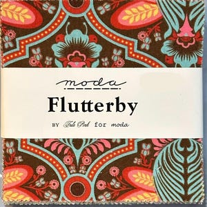 May include: A stack of fabric squares with a floral pattern in brown, teal, pink, and orange. The fabric is wrapped with a white band that reads "moda Flutterby by Tula Pink for moda."