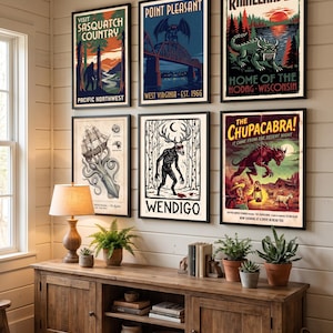 Puede incluir: Seis pósteres verticales enmarcados con ilustraciones de críptidos: Sasquatch, Point Pleasant, Hodag, Kraken, Wendigo y Chupacabra, dispuestos en dos filas sobre una pared blanca con marcos de color negro.