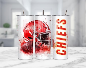 May include: A white cylindrical tumbler with a metal straw featuring a red football helmet graphic, a football, and red watercolour splatter accents. The word CHIEFS is printed vertically in bold red letters with a yellow outline on the side.