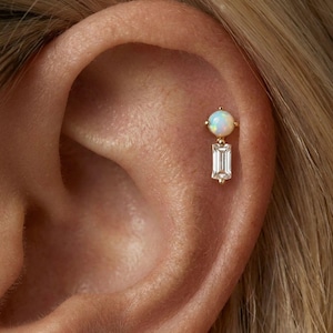 Op de afbeelding: Een set van drie keramische mokken met een gespikkelde, matte afwerking. De mokken zijn in crème, lichtgrijs en donkergrijs. Elke mok heeft een eenvoudig, modern ontwerp en een afgeronde handgreep. De mokken zijn op elkaar gestapeld.