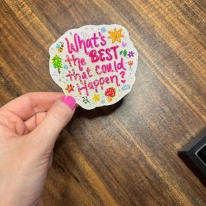 May include: A die-cut sticker with a holographic finish featuring the pink text "What's the BEST that could happen?" surrounded by small colourful illustrations of a sun, a bee, a mushroom, flowers, and stars on a white background.