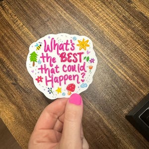 May include: A white die-cut sticker with a scalloped edge featuring the pink text What's the BEST that could Happen? surrounded by colourful illustrations of a bee, a sun, a green tree, a red mushroom, a blue cloud, and various small flowers.
