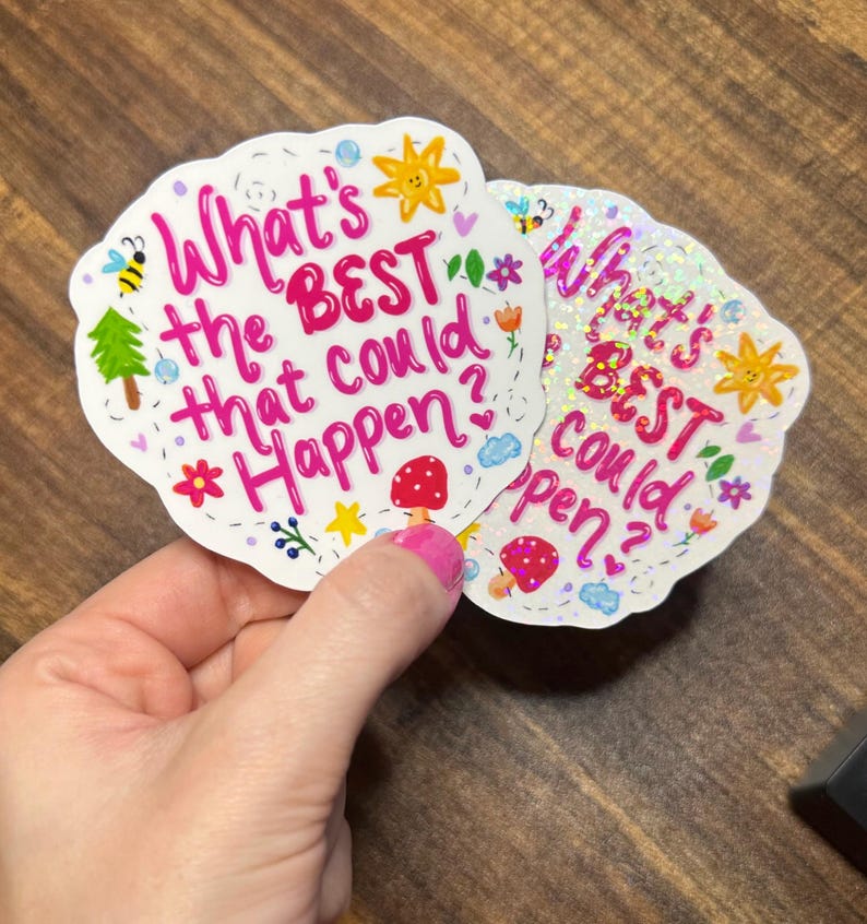 May include: Two die-cut stickers with a scalloped edge featuring the pink text What's the BEST that could happen? surrounded by colourful illustrations of a yellow sun, a green tree, a red mushroom, a bee, and small flowers on a white background.