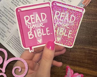 May include: Two square stickers featuring a pink book design with the white text READ your BIBLE. One sticker has a solid pink finish, while the other has a holographic glitter effect. Both stickers include a white cross and heart graphic.