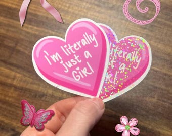 May include: Two heart-shaped stickers with a pink background and white text that reads I'm literally just a Girl. One sticker has a smooth finish, while the other features a holographic glitter texture. Decorative elements include a pink bow, a pink butterfly, a pink flower, and a pink swirl.