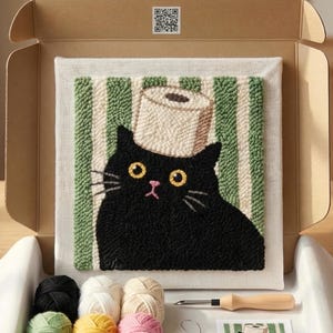 May include: A punch needle kit with a black cat design wearing a toilet roll hat. The cat is set against a green and white striped background. The kit includes various coloured yarns, a punch needle tool, and a printed pattern.