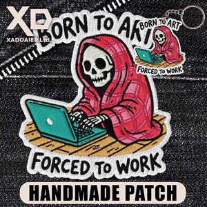 May include: Embroidered patch featuring a skeleton in a red plaid robe, working on a teal laptop. The text "BORN TO ART" and "FORCED TO WORK" are included. The patch is labeled "HANDMADE PATCH".