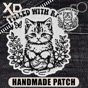 May include: A black and white embroidered patch featuring a cat holding yarn, surrounded by flowers and the text "FILLED WITH RAGE". A matching keychain is also visible. The words "HANDMADE PATCH" are at the bottom.