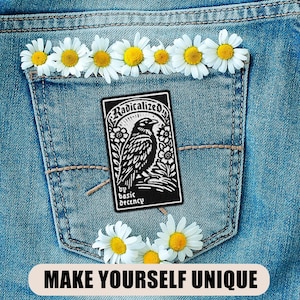 May include: A denim pocket adorned with daisies and a black patch featuring a raven illustration and the text "Radicalized by basic decency." The phrase "MAKE YOURSELF UNIQUE" is displayed at the bottom.