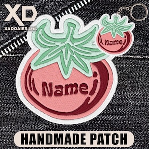 May include: A tomato-shaped embroidered patch and a matching tomato-shaped keychain. Both items feature a light pink tomato body with a dark red accent, a light green stem, and the word Name embroidered in dark red thread on the tomato surface.