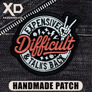 May include: Embroidered patch with the words "EXPENSIVE DIFFICULT & TALKS BACK" in a circular design. The patch is black and white, with a skeleton hand giving a peace sign. The words "HANDMADE PATCH" are at the bottom.