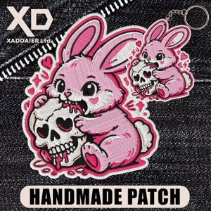 May include: Embroidered pink bunny patch with a skull, hearts, and the text "HANDMADE PATCH". The bunny is biting the skull. A smaller keychain version of the bunny is also present. The patch is on a denim background.