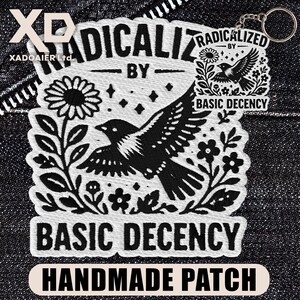 May include: A black and white embroidered patch featuring a bird design and the text "RADICALIZED BY BASIC DECENCY". The patch also includes the words "HANDMADE PATCH". A small keychain is attached.