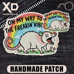 May include: Embroidered patches with a possum design and the text "ON MY WAY TO THE FREAKIN' VIBE WEIRD." The patches feature a rainbow, flowers, and a keychain. The words "HANDMADE PATCH" are also visible.