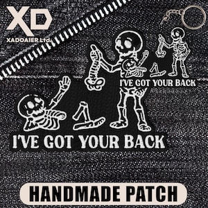 May include: Black and white embroidered patches with skeleton designs. The patches feature the text "I'VE GOT YOUR BACK" and "HANDMADE PATCH". A keychain with a skeleton charm is also visible.
