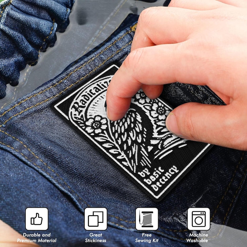 May include: A black and white embroidered patch with the text "Radicaliz" and "by basic Decency". The patch features a floral and bird design. The patch is being held over a denim surface.