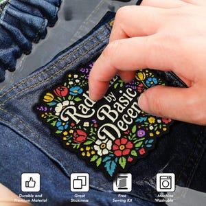 May include: A black patch with the text "Rad by Basic Decent" surrounded by colorful floral embroidery. The patch is being held over a denim surface. The patch is durable, has great stickiness, includes a free sewing kit, and is machine washable.