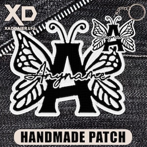 May include: A black and white butterfly-shaped patch and keychain featuring the letter "A" and the word "Anyname" in script. The items are set against a denim background. The text "HANDMADE PATCH" is at the bottom.