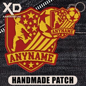 May include: Embroidered red and yellow soccer patch with the text "ANYNAME" and "HANDMADE PATCH". The patch features a soccer ball, stars, and a soccer player. A matching keychain is attached.