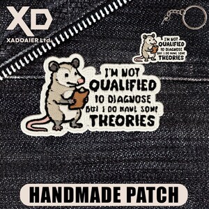 May include: Embroidered patches featuring a cartoon opossum holding a clipboard, with the text "I'M NOT QUALIFIED TO DIAGNOSE BUT I DO HAVE SOME THEORIES." Includes a keychain and a "HANDMADE PATCH" label.