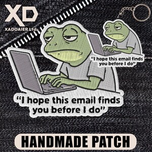 May include: Embroidered patch featuring a green frog with a laptop, and the text "I hope this email finds you before I do." A smaller keychain version is also visible. The patch is labeled "HANDMADE PATCH."