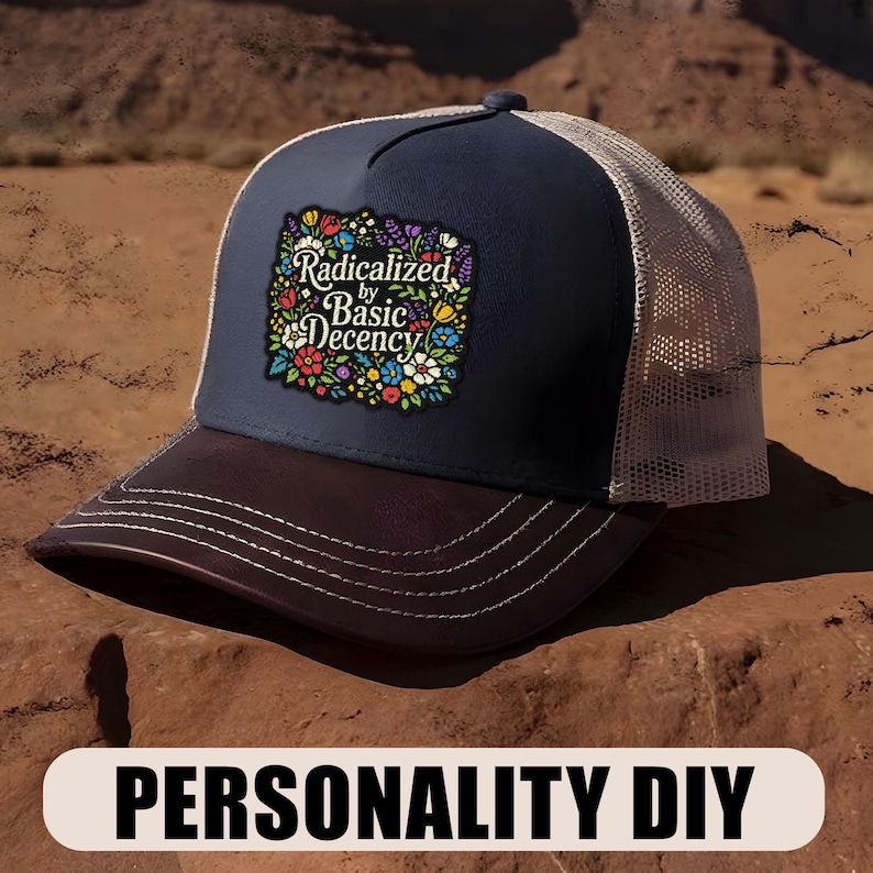 May include: A navy blue trucker hat with a brown brim and a beige mesh back. The front patch features the text "Radicalized by Basic Decency" surrounded by colorful flowers. The hat is a Personality DIY item.