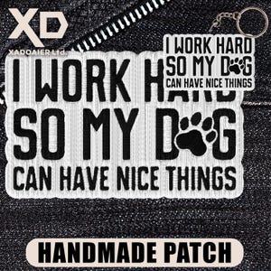 May include: A white embroidered patch with the text "I WORK HARD SO MY DOG CAN HAVE NICE THINGS". A small keychain with the same text is visible. The patch also says "HANDMADE PATCH".