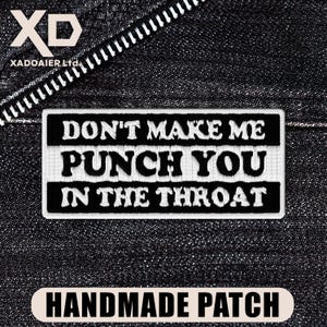May include: A black and white handmade patch with the text "DON'T MAKE ME PUNCH YOU IN THE THROAT." The patch is rectangular and has a stitched border. The background is a dark denim fabric.