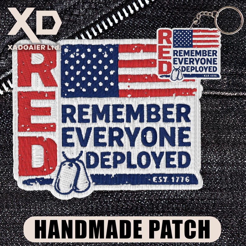 Pode incluir: Um patch feito &agrave; m&atilde;o com o texto "RED" em vermelho, um design da bandeira americana e as palavras "REMEMBER EVERYONE DEPLOYED". Inclui um porta-chaves com um design semelhante. O patch tamb&eacute;m apresenta etiquetas de identifica&ccedil;&atilde;o e o texto "EST. 1776."