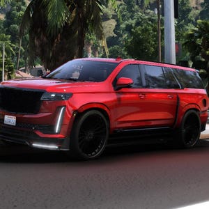 Puede incluir: Un SUV rojo con ruedas negras está estacionado en una calle. El vehículo tiene una parrilla negra y una placa de matrícula. El coche está frente a un fondo verde de árboles y edificios.