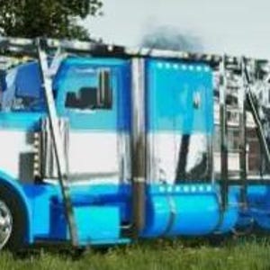 May include: A large, blue and white semi-truck with chrome accents and a specialized trailer. The truck has a tall cab and a long trailer designed for hauling oversized cargo. The vehicle is parked on a grassy area.