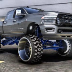 Puede incluir: Una camioneta Ram gris con neumáticos de gran tamaño y suspensión elevada. La camioneta tiene una parrilla cromada y componentes de suspensión azules. Los neumáticos tienen un dibujo profundo y llantas cromadas.