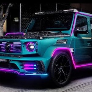 May include: A teal SUV with black wheels and neon purple and blue accent lighting. The vehicle has a black roof rack and a custom front bumper. The image is taken at night, with a person standing in the background.