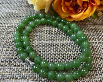 May include: A necklace composed of smooth, round, translucent green beads strung together in a circular pattern. The beads are uniform in size and feature a polished finish. A small, silver-toned metal clasp connects the two ends of the strand.