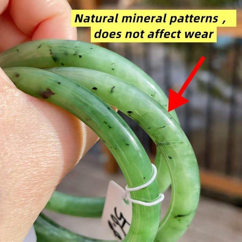 May include: Three jade green bangles with natural mineral patterns and black inclusions are displayed. The text in the image reads: "Natural mineral patterns, does not affect wear."