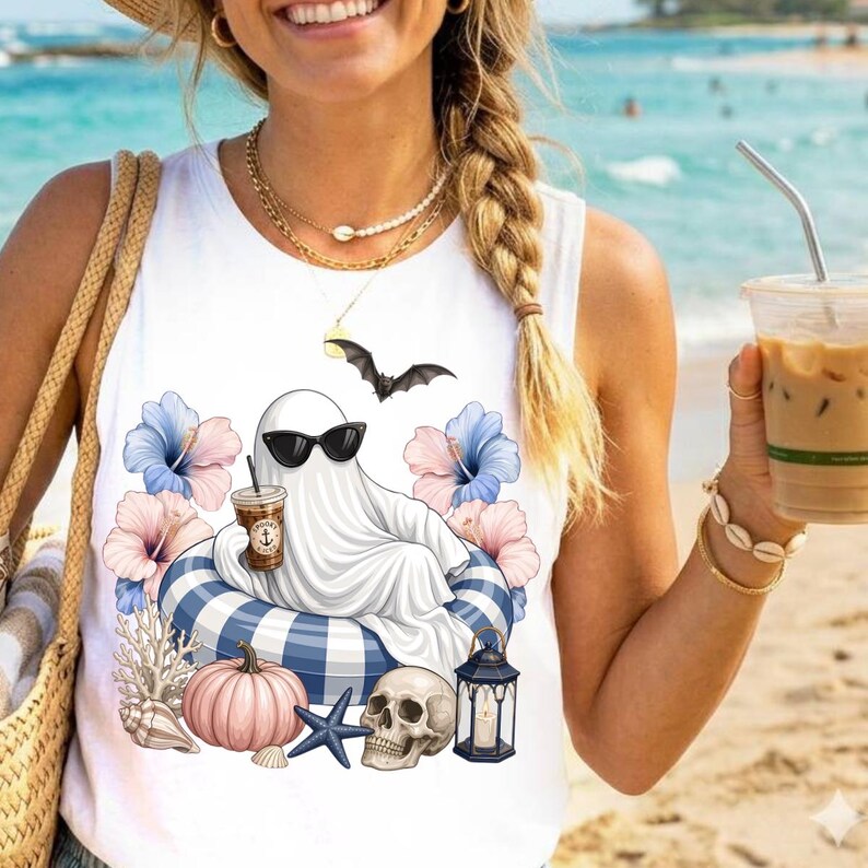 Op de afbeelding: Witte tanktop met een afbeelding van een spook met zonnebril, ontspannen op een blauw-wit gestreepte zwemband, met een koffie. Het ontwerp bevat bloemen, een vleermuis, een pompoen, een schedel en een zeester.