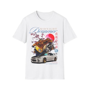 May include: White t-shirt featuring a graphic of a gold-colored engine and a white sports car. The design includes the text "Midnight Dreamer" and Japanese characters, with a red sun and cherry blossoms.