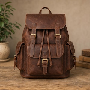 Puede incluir: Una mochila de cuero marrón con una solapa superior con dos correas verticales, hebillas de latón y cierre de cordón. La bolsa incluye un bolsillo frontal grande con una correa de hebilla y dos bolsillos laterales con hebillas de latón.