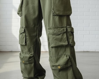 May include: Olive green cargo trousers with multiple pockets and a loose fit. The trousers are worn with a grey t-shirt and white trainers with green detailing. The trousers have a button fastening and are made of a robust fabric.