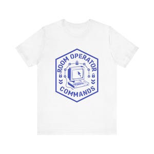 May include: White t-shirt with a blue graphic. The graphic is a hexagon with the words "ROOM OPERATOR COMMANDS" around a vintage computer monitor icon. The monitor displays a cursor. The design includes lock icons.